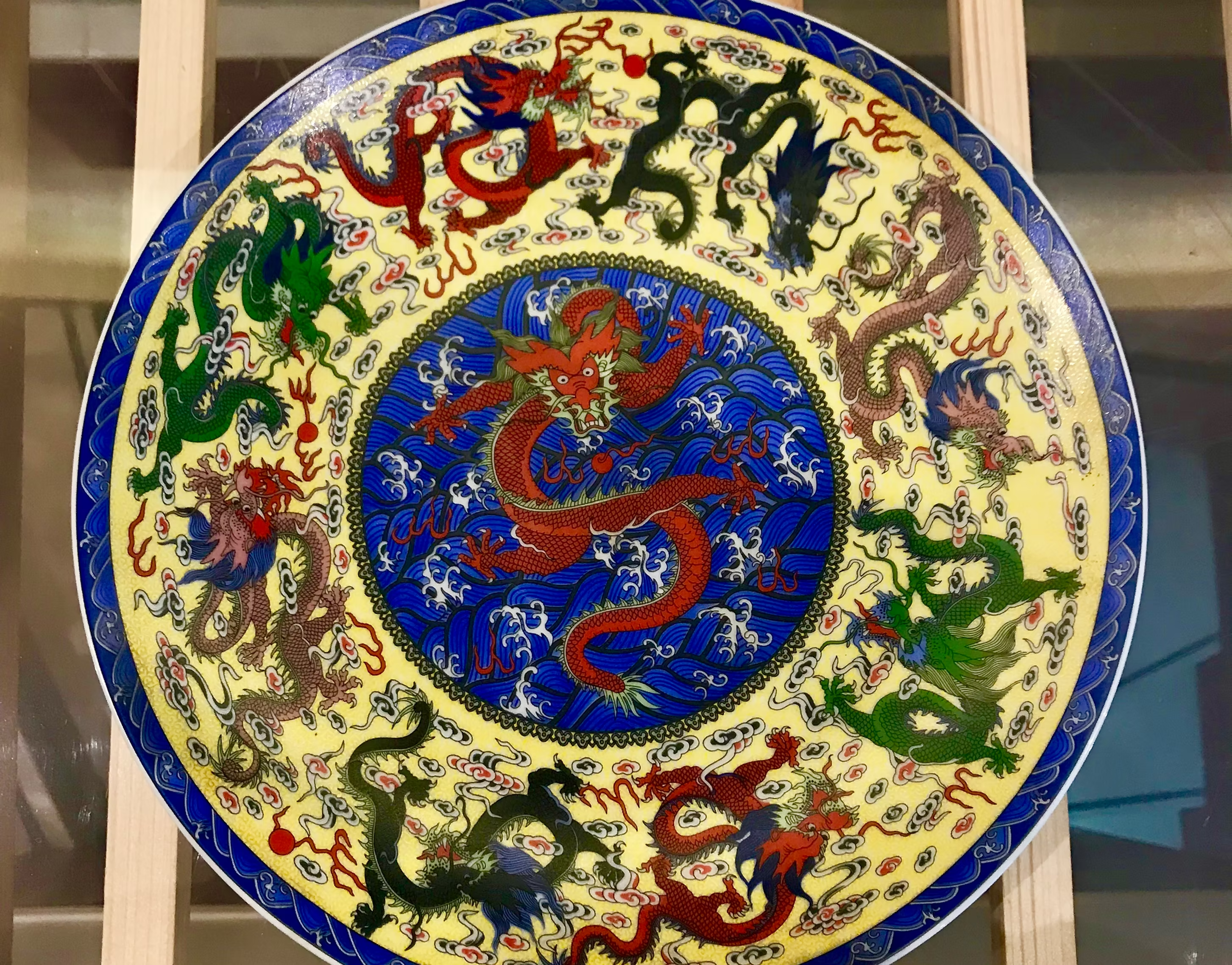 Dragon rouge peint au centre d'un plat en porcelaine, sur des vagues bleues